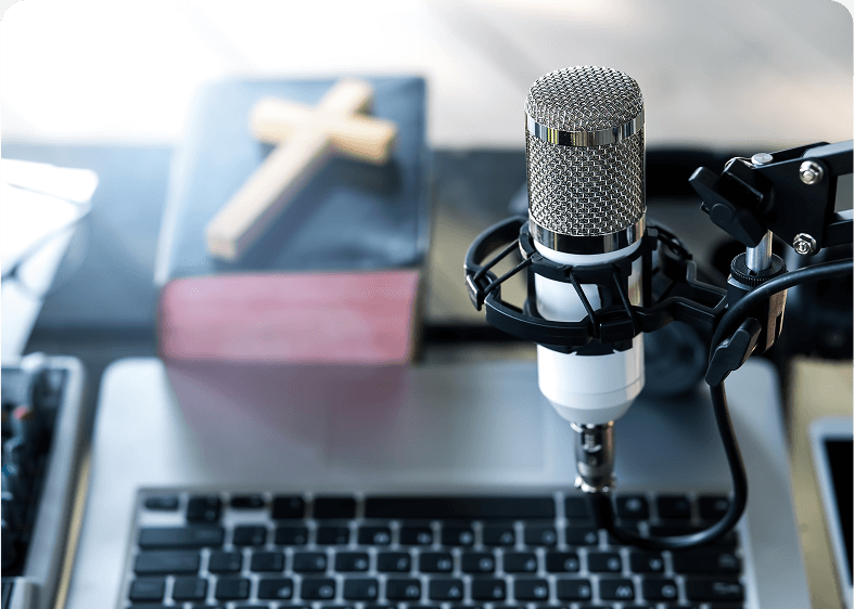 Microphone, laptop, and book with cross.