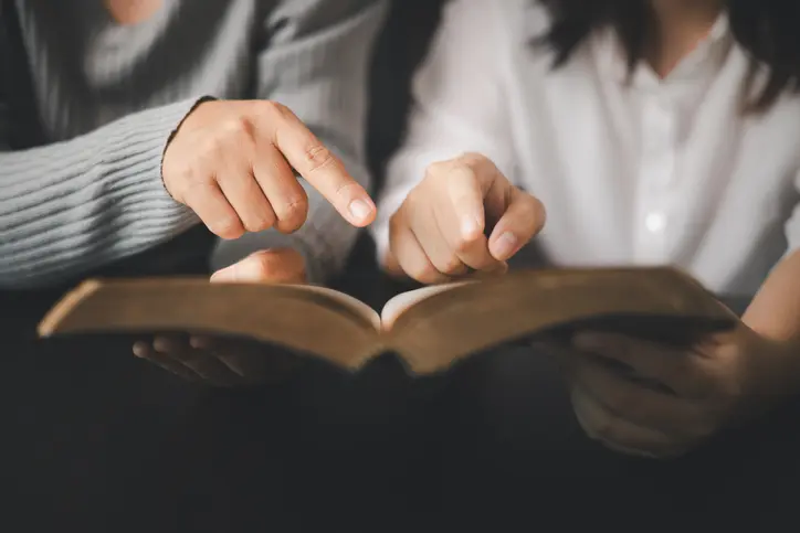 In the church, people to read Bible together, strengthening their faith as devout Catholics united by teachings of holy book. Christians are congregants join hands to pray and seek blessings of God.